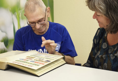 Menschen beim Durchblättern einer Briefmarkensammlung
